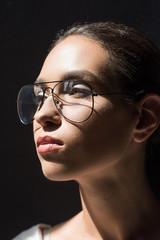 Fototapeta na wymiar portrait of attractive woman posing in stylish eyeglasses, isolated on black