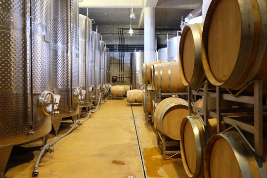 Interior of a modern underground winery with aluminium tanks and wine barrels