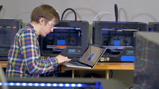 A young engineer debugs a 3d-printing problem. 
