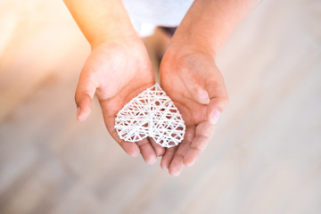 Child holding white heart in hands. Charity, love, care, support concept