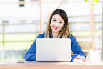 Obraz na płótnie Canvas Smiling beautiful young girl using laptop computer