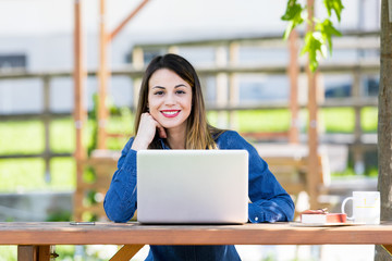 Beautiful happy young girl using laptop outdoors