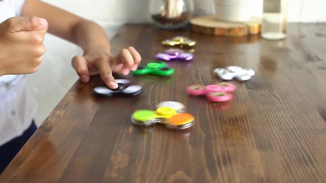 Child having fun outdoors with Spinner, slow motion. Young caucasian girl showing skills by flicking spinners with finger in the summer park.