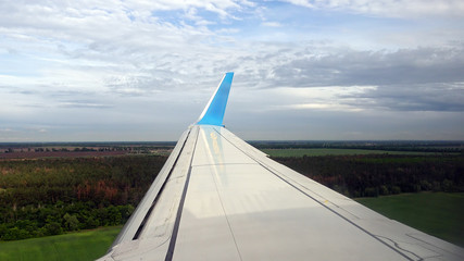 Fototapeta na wymiar Plane is preparing for landing in European airport. Flying over green forest fields and meadows.