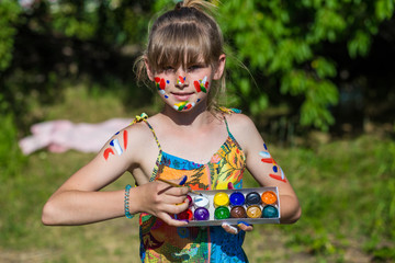 Cheerful cute girl playing with bright paints in the park. Have fun. Art and painting concept