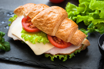 Croissant sandwich with ham, cheese, lettuce and tomato