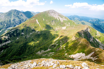 Górska panorama z zielonym szczytem na pierwszym planie. - obrazy, fototapety, plakaty