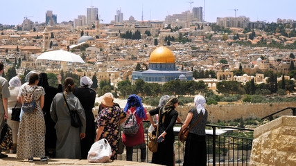 The Christian orthodox guide shows the Jerusalem Old City view to the pilgrims and tourists from the Mount of Olives. Famous Holy Land place and fantastic city view. - obrazy, fototapety, plakaty