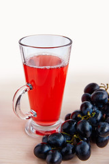 A glass of juice and black grapes