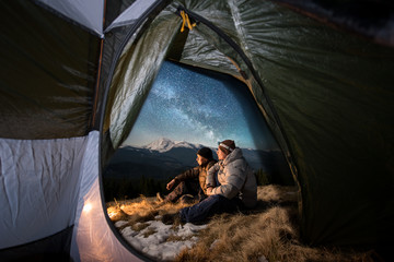 View from inside a tent on the two male tourists have a rest in the camping in the mountains at...