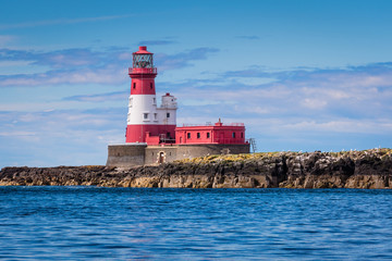 Fototapeta na wymiar Longstone Lighthouse at Farne Islands / Longstone Rock Lighthouse was made famous as the base for Grace Darling's rescue of survivors from a shipwreck