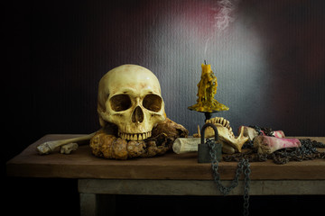 Still Life of skull and bone with fetters and candle on the wooden plank in dim light night