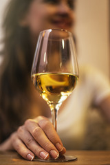 Close up of woman hands holding a glass of white wine in a bar.