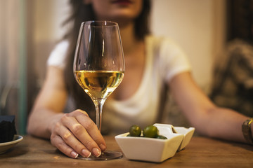 Close up of woman hands holding a glass of white wine in a bar.