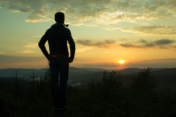 Fototapeta premium Guy with the Smoking pipe looking at mountainous landscape at sunset