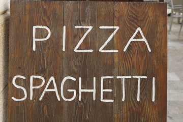 Handwritten sign on wooden board, Sign for pizza and spaghetti written in white letters