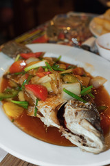 Fish stewed with vegetables on a plate, close-up