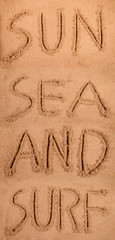 Sun sea and surf written in soft wet sand on a beach