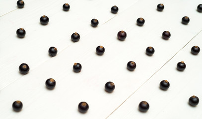 Fresh blackcurrants on white wooden background, copy space. Black currants natural pattern background. Blackcurrant arranged in rows. Summer and healthy food concept