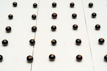 Fresh blackcurrants on white wooden background, copy space. Black currants natural pattern background. Blackcurrant arranged in rows. Summer and healthy food concept