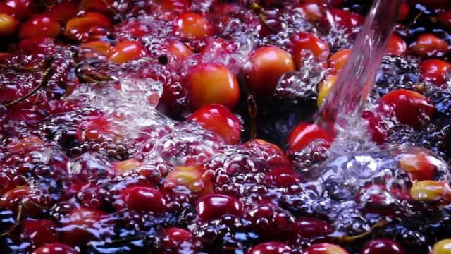 Amazing powerful water flowing and splashing red and yellow cherry berries in slow motion. Shooting with high-speed, 240fps, camera. Flat lay of yummy fresh fruit with amazing texture in full HD clip.