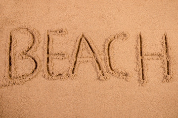 Beach written in soft wet sand on a beach