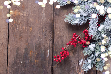 Spruce branches, decorative berries and holiday light  on aged wooden  background.