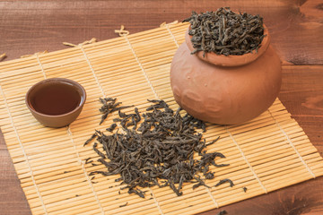 Hot, fresh tea with a kettle and a pot with cups on the mat