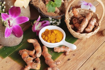 Turmeric root with turmeric powder on wood background