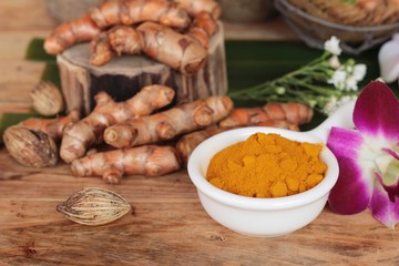 Turmeric root with turmeric powder on wood background