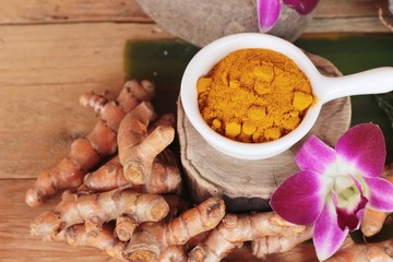 Turmeric root with turmeric powder on wood background