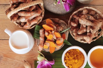 Turmeric root with turmeric powder on wood background