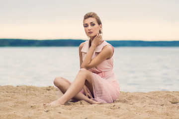 Fototapeta na wymiar Young girl sitting on the beach in the sea background.