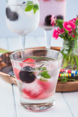 Glasses of water with ice cubes with fresh berries.