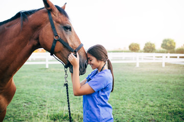 Vet petting a horse outdoors at ranch. 