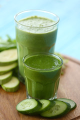 Glasses with fresh tasty vegetable smoothies on wooden board