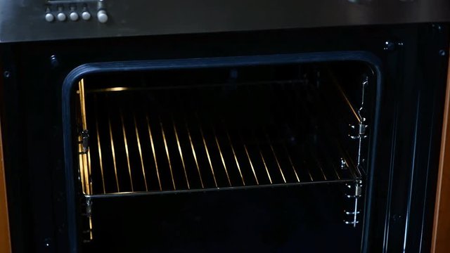 Woman put batter for cupcakes in oven in kitchen closeup. Cooking time.