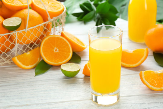 Glass of fresh orange juice with fruits on wooden background
