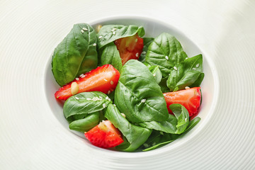 Plate with spinach leaves and strawberry, close up