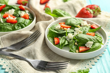Plates with spinach leaves, strawberry and cheese on napkin