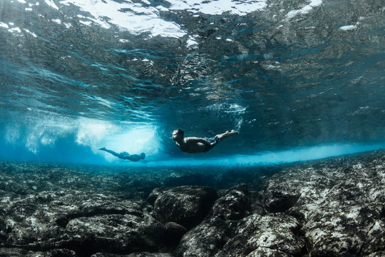 Men Swimming Underwater In Ocean