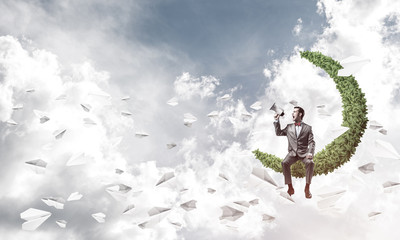 Businessman announcing something in loudspeaker and paper planes