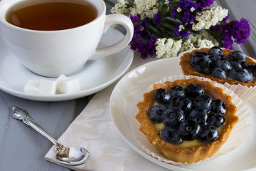 Breakfast: cake with blueberries and tea on the grey background   