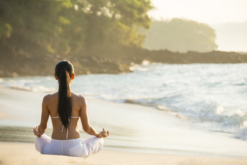 Rear view of woman sitting in a yoga lotus position on the beach, Bali, Indonesia