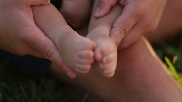 Tiny baby feet in caring father's hands