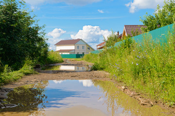 Puddles on a dirt road in a village in sunny weather