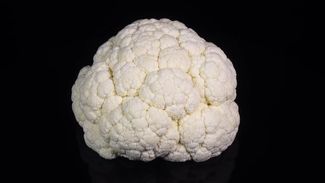 Amazing side view of whole cauliflower, rotating to the left on black background. Vibrant natural texture close up in 4k, 3840x2160, clip. Excellent eco product for healthy food.

