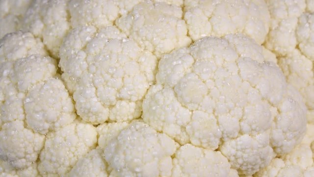 Amazing water sprinkling of cauliflower white side, rotating to the left. Vibrant natural texture close up in 4k, 3840x2160, clip. Eco product for healthy food.
