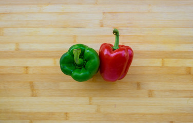 Red and green bell pepper on wooden table, top view with copy space