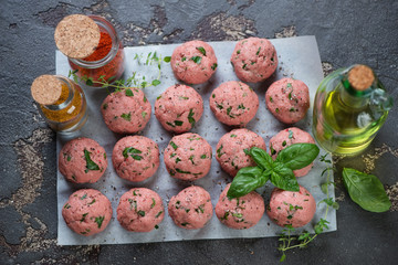 Baking paper with raw fresh meatballs on a brown stone background, high angle view, studio shot